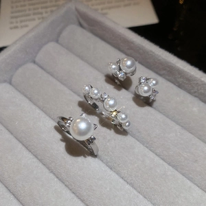 Detailed view of elegant pearl jewelry set with zircon accents on a gray velvet tray