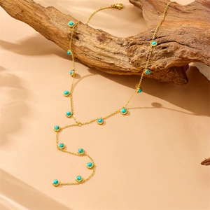 Minimalist gold Y-shaped necklace with turquoise beads draped over natural wood