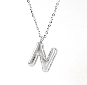 Macro shot of silver puffy 3D letter N pendant on a stainless steel chain necklace