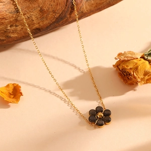 Close-up of golden necklace featuring a dark floral pendant with cat eye stone detailing