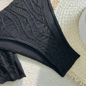Detail der schwarzen Bikinihose mit strukturiertem Fischgrätmuster für Bademode