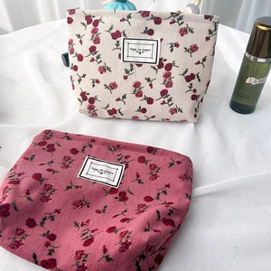 Close-up of beige and red floral corduroy cosmetic bags with Time To Party labels