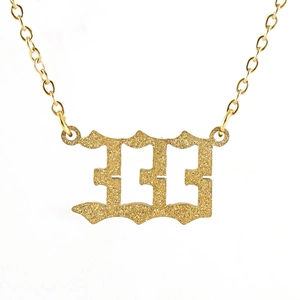 Macro view of gold number 333 necklace featuring a textured frosted finish and o-chain