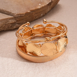 Three-piece gold geometric bangle set including spiral knot and textured disk bracelet