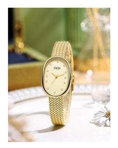 Detail of golden oval watch featuring crystal indices and textured mesh strap