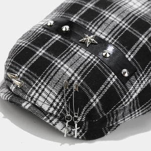 Detail of plaid beret featuring silver star metal logo and punk style cross pendant charm