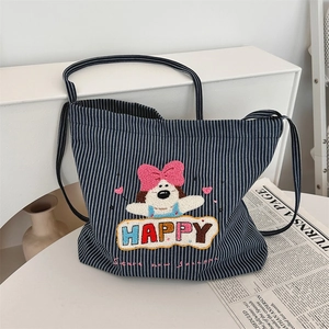 Detail of striped canvas tote bag featuring 3D embroidered cartoon dog and HAPPY text