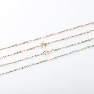 Detail of gold stainless steel bead chains with colorful enamel pink and blue charms