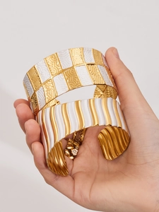 Detailansicht breiter Armreifen mit goldenen und weißen Emaille-Geomustern
