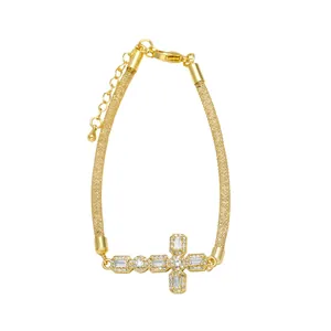 Detalle de pulsera de cruz dorada con cadena de malla fina y circonitas engastadas