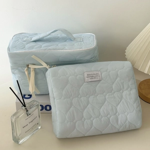 Detailed view of light blue quilted cosmetic bag set with heart patterns and soft texture