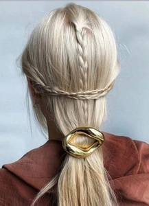 Golden irregular oval hair clip shown on blonde hair styled in a braided ponytail