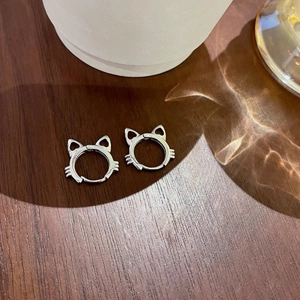 Detailed view of silver cat-shaped earrings on a wooden background with elegant reflections