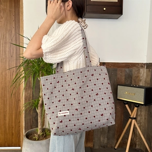 Détail du sac cabas en toile à pois rouges et nœud décoratif porté par le mannequin