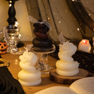 Detail of snake-shaped scented candle with rose top on wooden stand and pumpkin decor