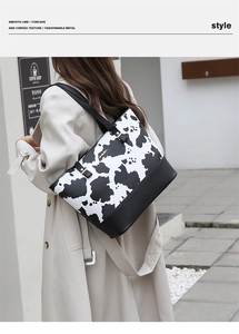 Gros plan d'un sac cabas à imprimé vache avec base en cuir et détails dorés sur modèle