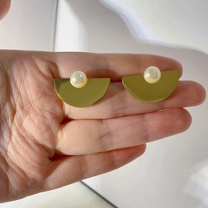 Detailed macro view of gold matte half-round earring with a central white pearl