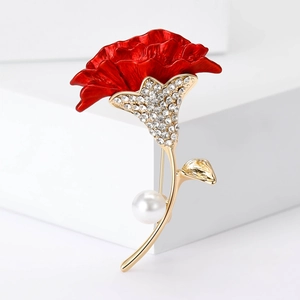 Detailed shot of red flower brooch with gold leaves, clear rhinestones, and white pearl