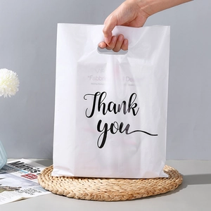 Close-up of hand holding a white Thank You plastic gift bag for boutique shopping