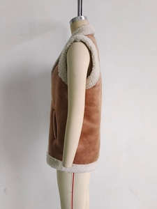 Detail view of brown suede vest featuring white faux shearling lining and side pockets