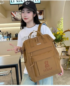 Detail of brown nylon backpack with cute bear embroidery and dual top handles