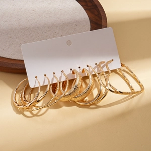 Detailed set of six pairs of gold hoop earrings in heart and round shapes on display card