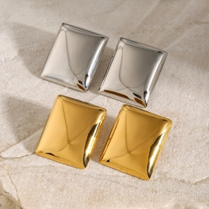 Polished 18k gold and silver rectangular geometric earrings on a stone surface