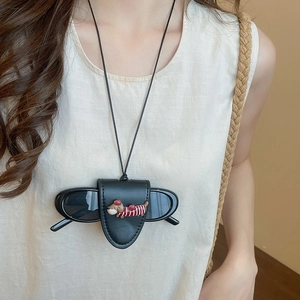 Detail shot of a black leather dachshund glasses holder necklace worn on a beige top