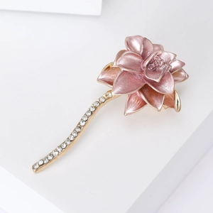 Macro detail of a pink enamel lotus flower brooch with gold plating and sparkling crystals