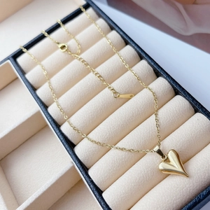 Close-up of a polished gold heart pendant necklace in a beige velvet jewelry box