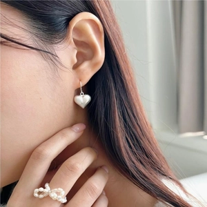 Close-up of matte brushed heart earring and pearl bow ring on a model with soft lighting