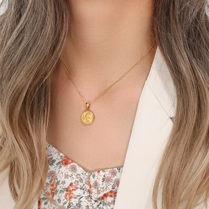 Close-up of golden necklace with a detailed snake relief on a round pendant pendant