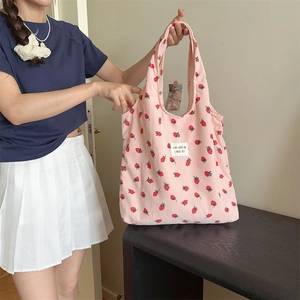 Détail du sac à bandoulière en velours rose avec imprimé fraise et étiquette