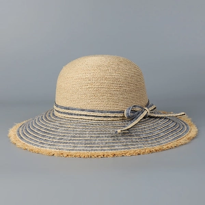 Detailed texture of woven straw sun hat with blue striped brim and frayed edges