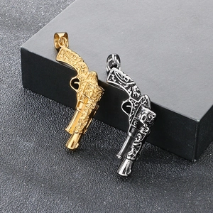 Detailed view of silver and gold stainless steel pistol pendants with intricate carvings