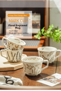 Close-up of hand-painted floral stoneware mugs with ergonomic handles on wood surface