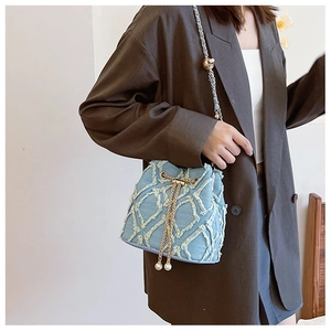 Detail of blue denim bucket bag with quilted pattern, pearl accent and chain strap
