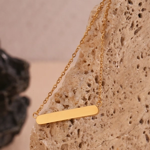 Gros plan détaillé d'un pendentif barre plaqué or 18K sur une chaîne minimaliste