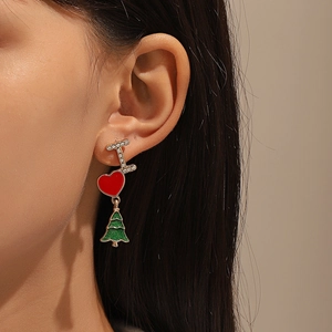 Detailed view of Christmas earrings with heart and tree pendants on a model