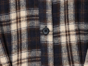 Detailed close-up of the plaid flannel fabric texture with a black button fastener