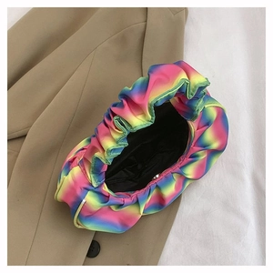 Top view of rainbow gradient pleated dumpling bag on beige suit fabric with sleek texture