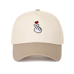 Detail of finger heart embroidery on a beige and khaki panelled cotton baseball cap