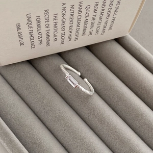 Detail of S925 silver twist band ring with square clear stone in a grey jewelry box