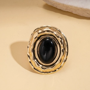 Macro detail of vintage gold ring with black oval stone and water ripple texture