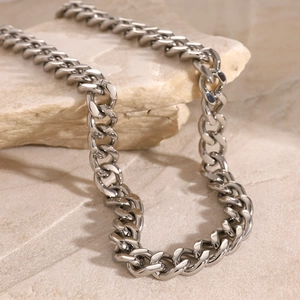 Close-up of silver Cuban chain necklace on minimalist stone background with soft lighting