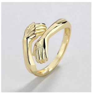 Detailed macro shot of golden hugging hands design on a minimalist metallic ring