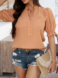 Detailed close-up of orange V-neck blouse with button detail and casual flare half-sleeves