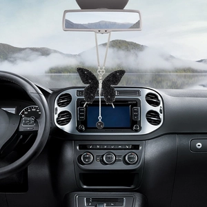Detailed view of a sparkling black crystal butterfly car pendant hanging on a rearview mirror