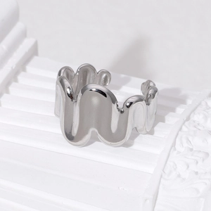 Detailed view of an irregular wavy silver stainless steel open ring on a stone base