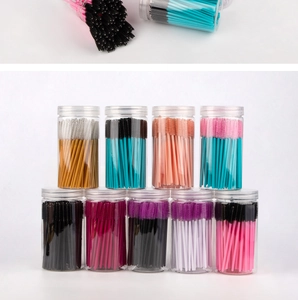 Detailed view of colorful disposable eyelash brushes in transparent cylindrical tubes